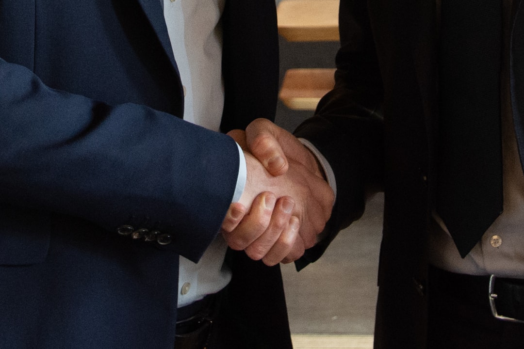 Business executives shaking hands on a deal, representing mergers and acquisitions - Corporate immigration law